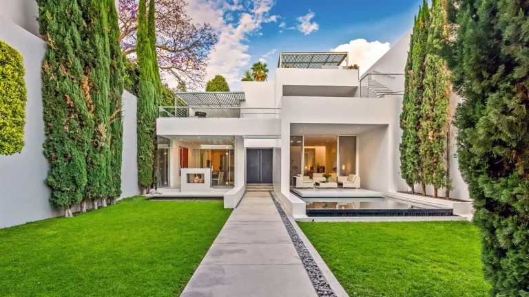 Buying-Real-Estate-in-San-Miguel-de-Allende-as-a-Foreigner - Colonial Real Estate - Colonial Real Estate Modern luxury home in San Miguel de Allende featuring contemporary white architecture, floor-to-ceiling glass walls, manicured garden, and rooftop terrace