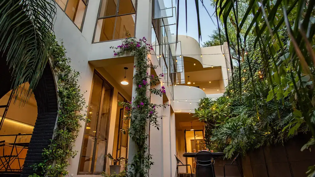 Modern luxury home courtyard in San Miguel de Allende with bougainvillea, lush gardens, and string lights, illustrating the ownership costs of high-end properties in the city.